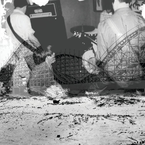Black and white image of a person playing guitar with a roller coaster in the background